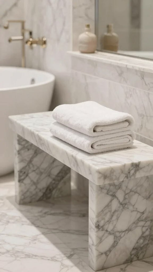 White marble bench in luxury bathroom with folded towels on top