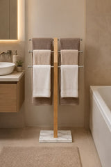 Freestanding wooden towel rack with marble base and stainless steel rails in bathroom